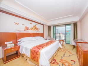 A hotel room with a large bed, a desk, a chair, and a balcony with a view.