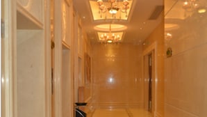 A long, narrow hallway with a polished floor and a large, ornate chandelier. - Vienna Hotel Qingyuan Taihe Ancient Cave (Qingyuan)