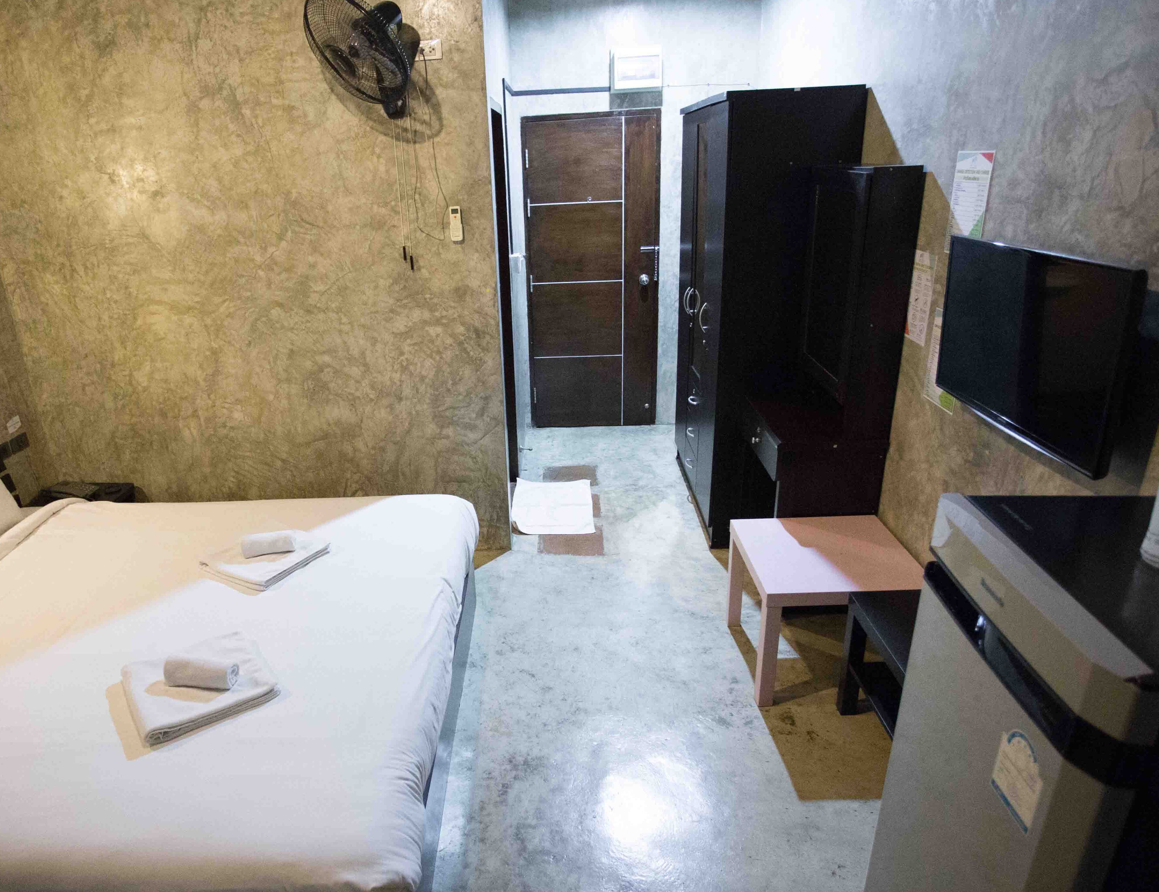 Una habitación de hotel con cama, escritorio, televisor y armario.