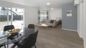 A modern living room with a sofa, coffee table, and dining area with chairs and a glass table.