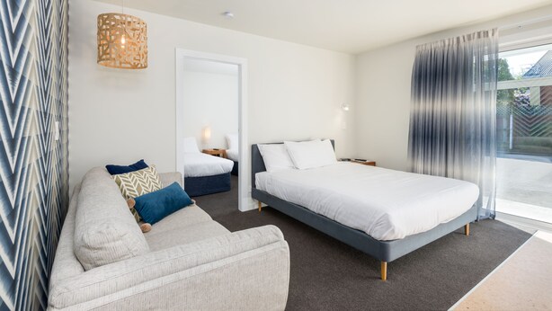 A modern bedroom with a sofa, a bed, a nightstand, and a hanging light fixture.