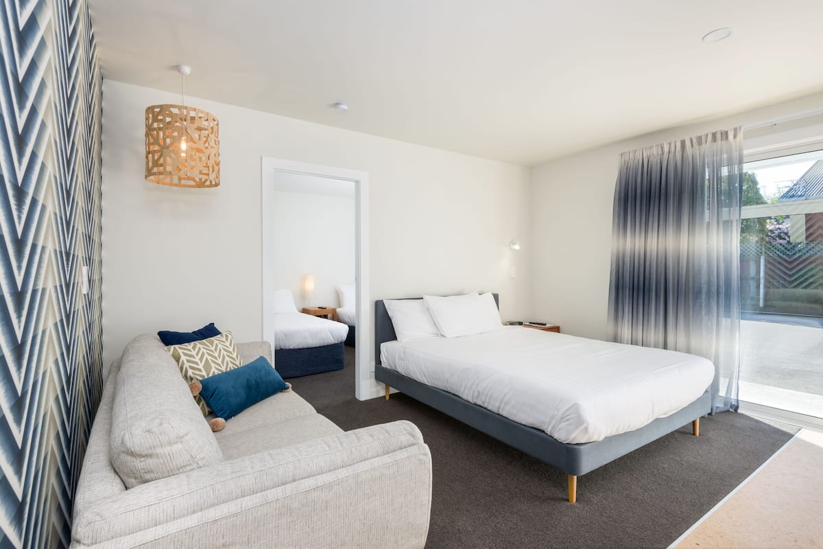 A modern bedroom with a sofa, a bed, a nightstand, and a hanging light fixture.