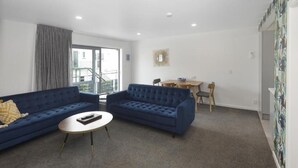 A living room with two blue sofas, a round coffee table, and a dining area with a table and chairs.