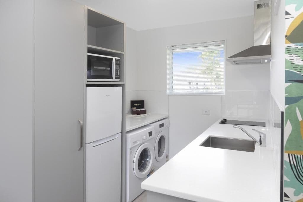 A compact kitchen with a built-in washing machine, a microwave, and a sink.