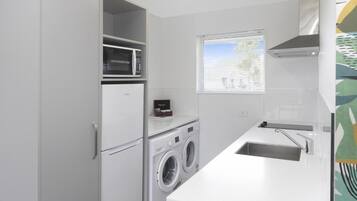 A compact kitchen with a built-in washing machine, a microwave, and a sink.