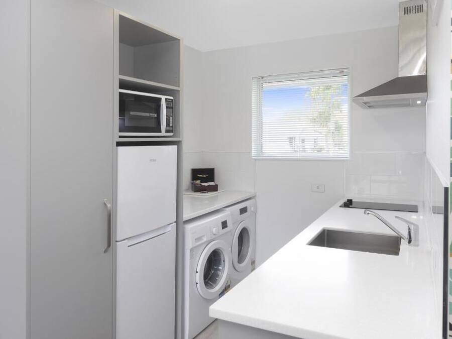 A compact kitchen with a built-in washing machine, a microwave, and a sink.