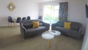 A living room with two grey sofas, a small white table, and a dining table with chairs.
