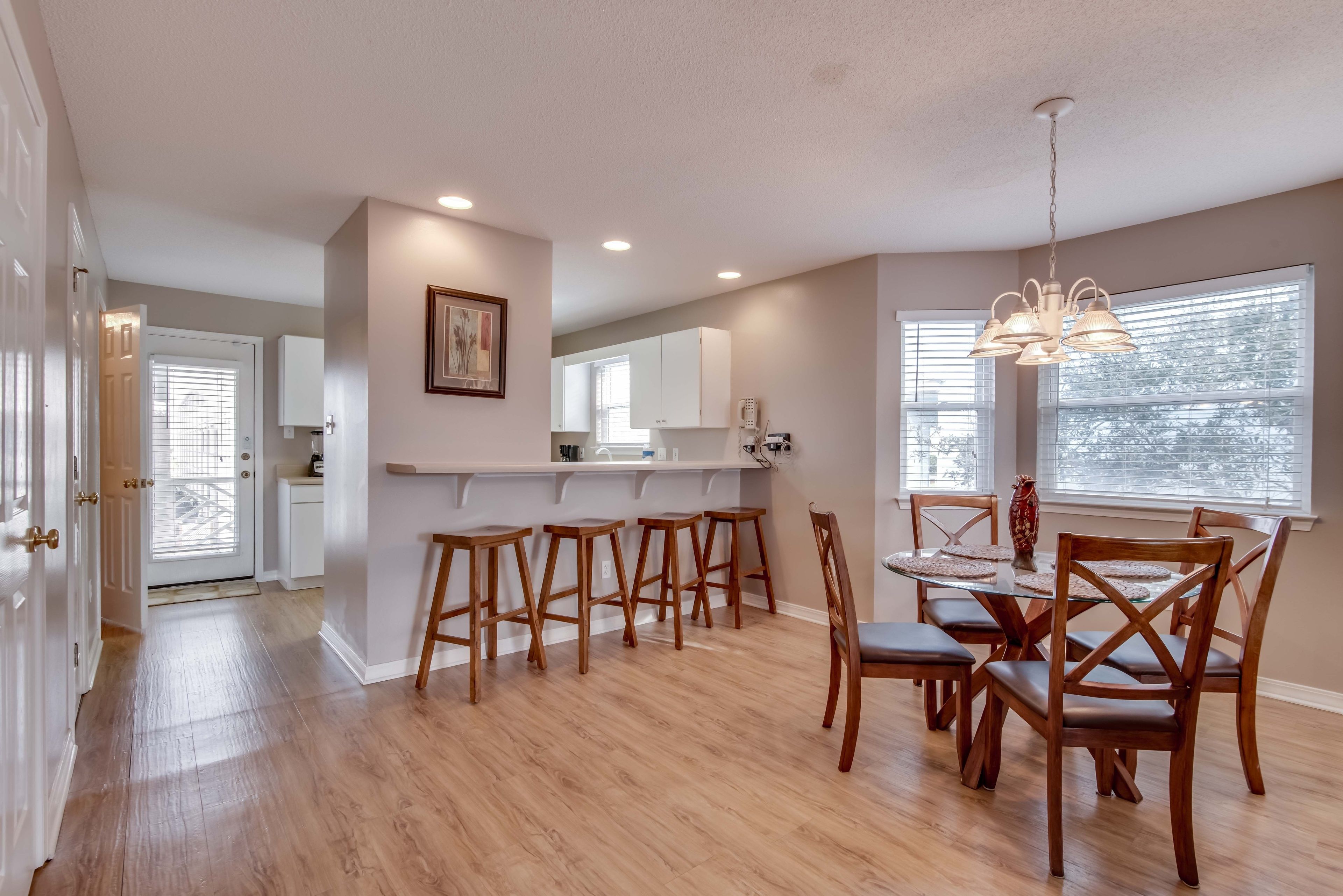 A spacious kitchen with wooden stools, a dining table with chairs, and a pendant light.