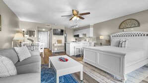 A modern living room with a grey sofa, a white coffee table, and a blue patterned rug. - Summersalt 1 Bedroom Condo by RedAwning (Santa Rosa Beach)