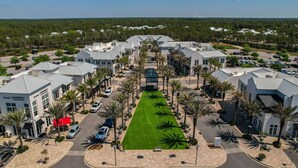 A hotel with a central lawn, multiple buildings, and parked cars. - Summersalt 1 Bedroom Condo by RedAwning (Santa Rosa Beach)
