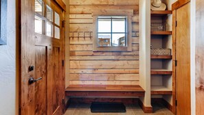 Un interno in legno con una finestra, una porta e uno scaffale con un cappello.