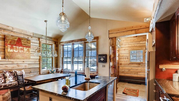 Cucina con pareti in legno, un'isola grande con lavello e luci a sospensione.