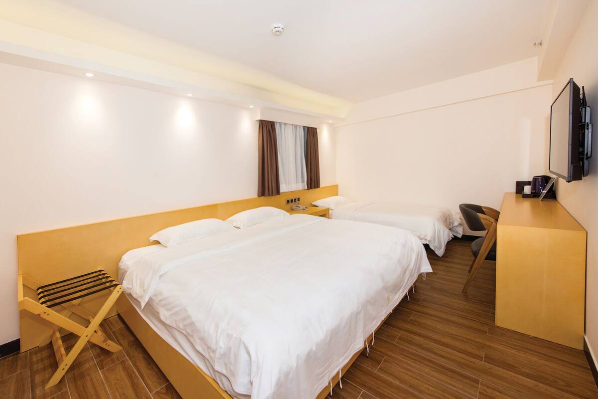 Una camera d'albergo con due letti, una scrivania, una sedia, una TV e un piccolo tavolo con un telefono.