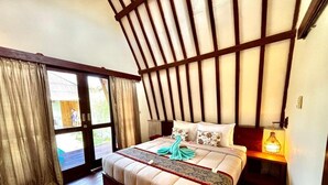 Ein Schlafzimmer mit Bett, Vorhängen, Holzboden, Nachttisch und Fenster.