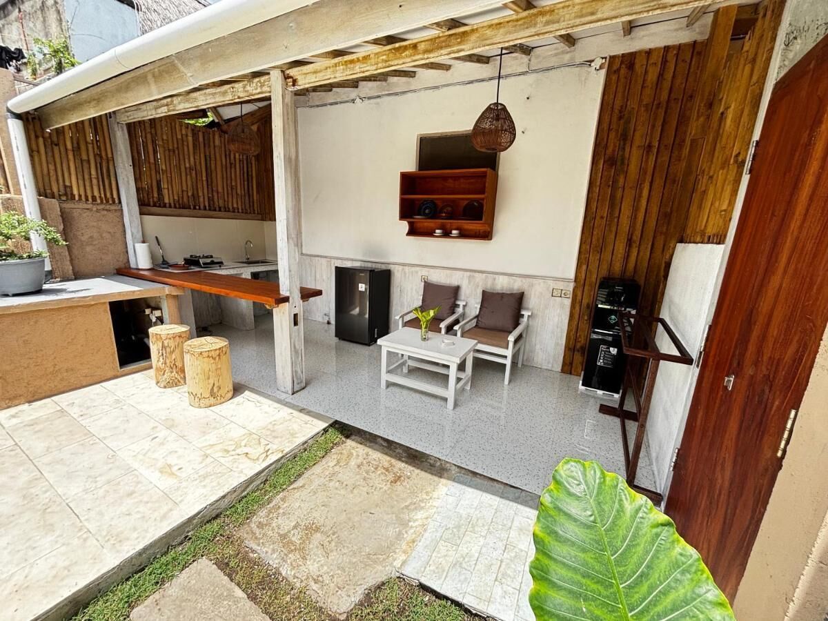 Uma área de pátio com um conjunto de assentos, uma pequena mesa e uma estante decorativa.