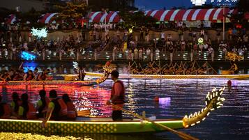 A nighttime dragon boat race with spectators on the shore.
