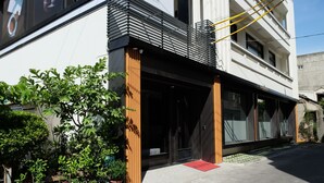 A modern building with a wooden facade, large windows, and a red mat at the entrance.