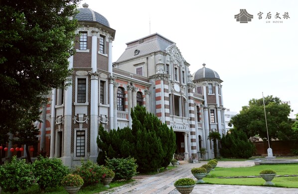 A large, historic building with multiple domes and columns, surrounded by well-maintained gardens and pathways.