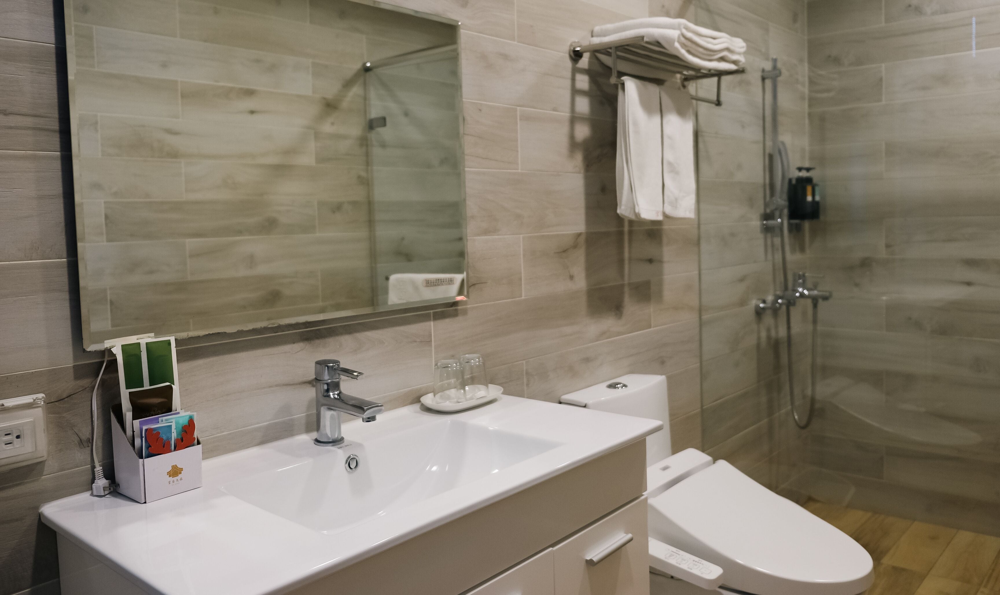 A modern bathroom with a large mirror, a sink, a toilet, and a shower area.