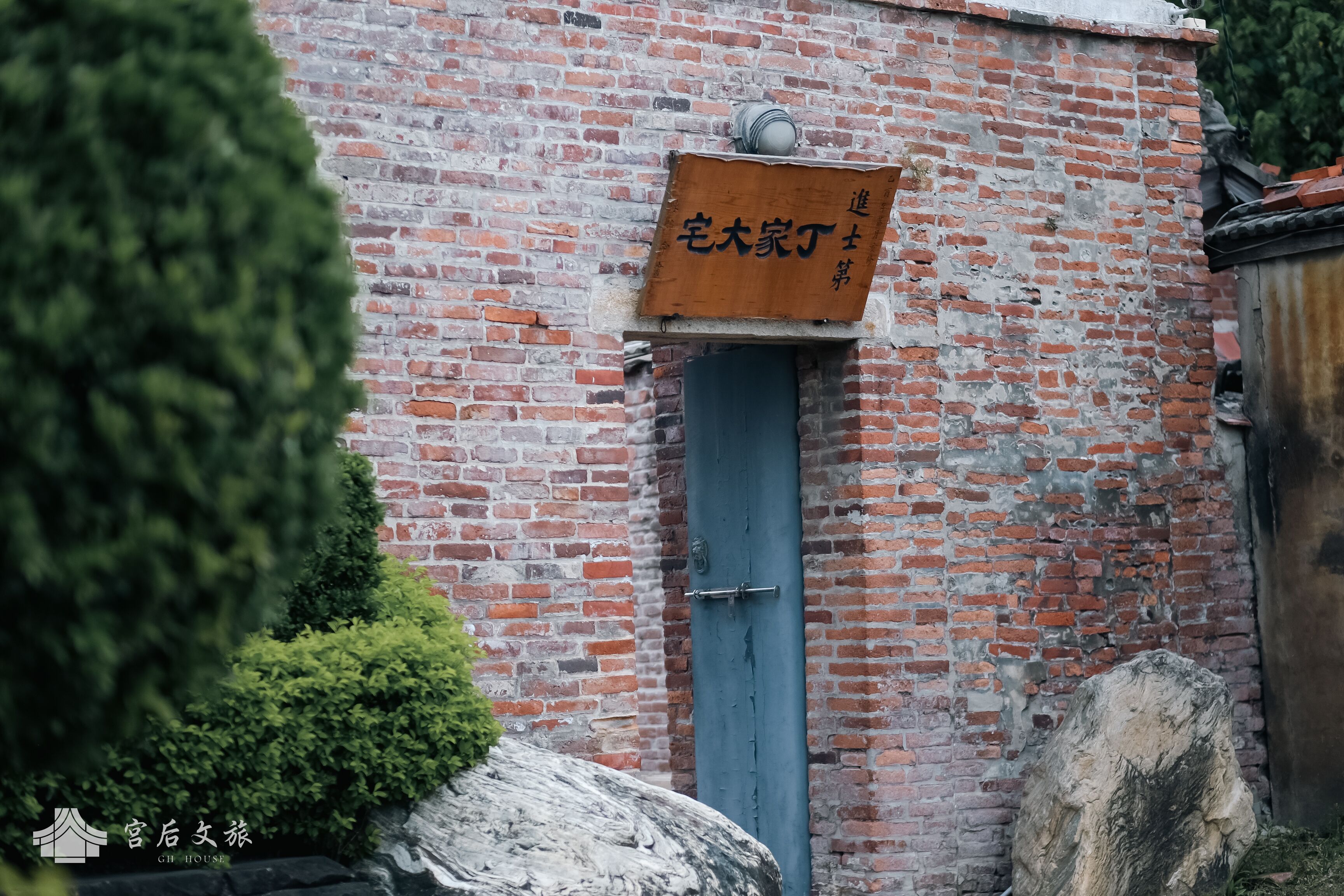 A brick building with a blue door and a signboard.