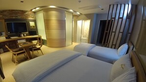 A hotel room with a large bed, a desk with a chair, a television, and a sliding door leading to a bathroom. - Khan Hotel (Daegu)