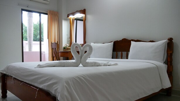 A neatly made bed with white linens and two towels arranged in a heart shape. - Dalha Renovtel Hotel (Nakhon Phanom)