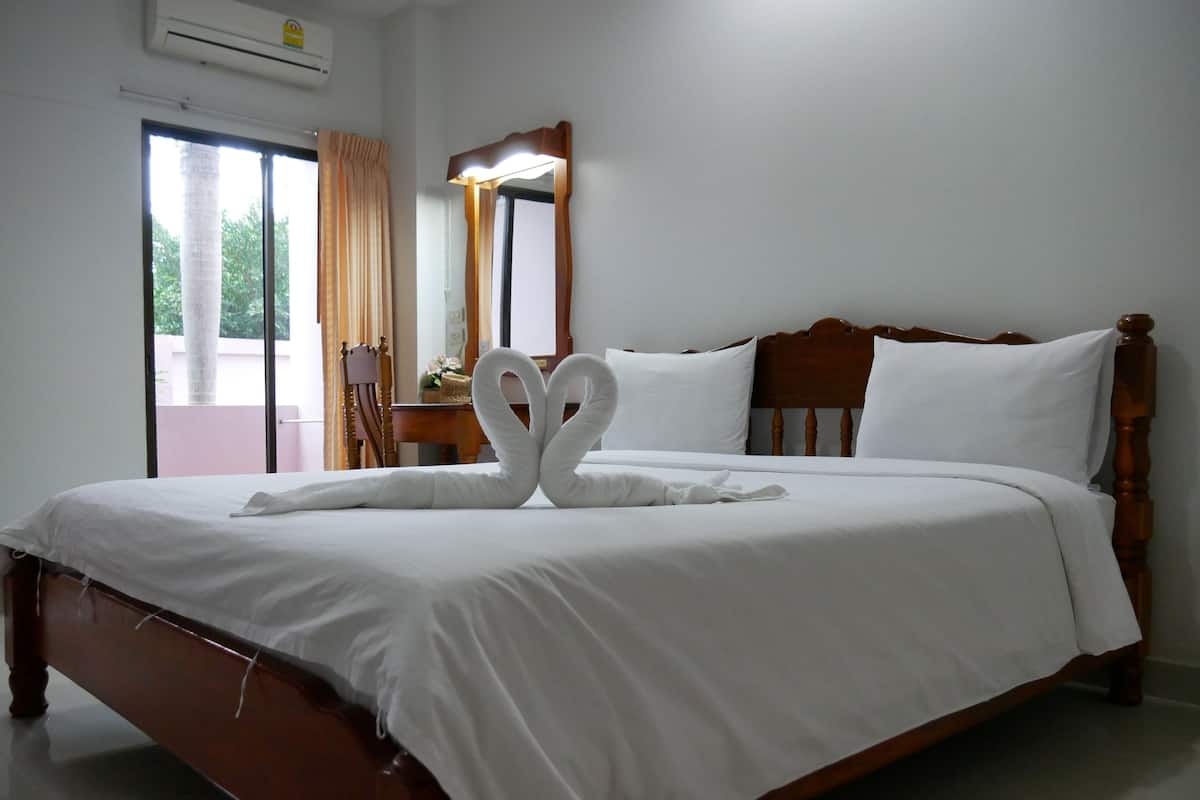 A neatly made bed with white linens and two towels arranged in a heart shape.