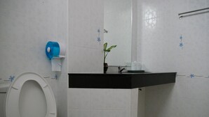A bathroom with a toilet, sink, and a small plant on the counter. - Dalha Renovtel Hotel (Nakhon Phanom)