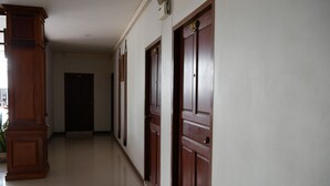 A hallway with wooden doors and a large wooden cabinet. - Dalha Renovtel Hotel (Nakhon Phanom)