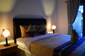 A neatly made bed with a quilt, two bedside lamps, and a window with curtains. - Meisya Cottage (Gili Trawangan)