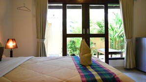A hotel room with a bed, a lamp, a towel, and a view of greenery outside. - Meisya Cottage (Gili Trawangan)
