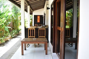 A covered outdoor dining area with a wooden table and chairs, a sink, and a mirror. - Meisya Cottage (Gili Trawangan)