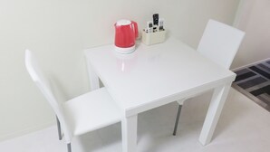Ein weißer Tisch mit einem roten Wasserkocher und einem Halter für Fernbedienungen.