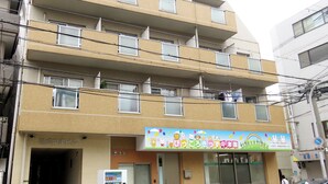 Ein mehrstöckiges Gebäude mit Kinderspielbereich im Erdgeschoss, mit einem bunten Schild und Zeichentrickfiguren.