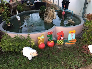 Ein Teich mit einem Flamingo, umgeben von bunten Tiermanipulationen und einer Schaf-Figur.