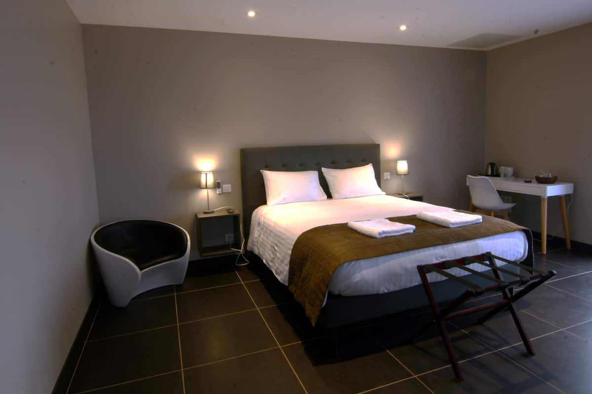 Una habitación de hotel moderna con una cama grande, lámparas de noche, un escritorio y una silla.