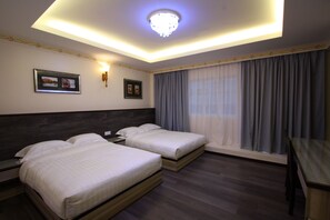 A hotel room with two beds, a desk, and a large window with curtains. - Shamrock Guest House (Ipoh)