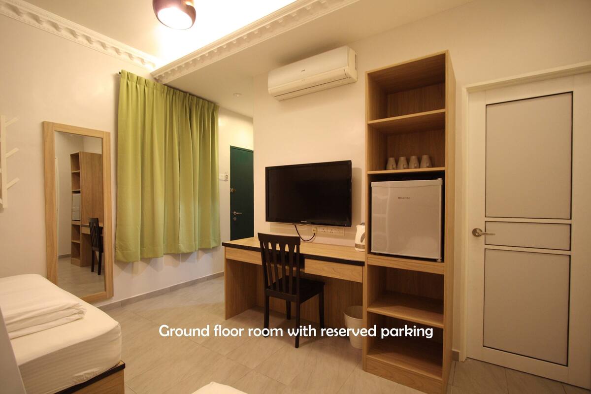 A ground floor room with a desk, chair, television, and a mini-fridge.
