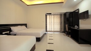 Une chambre d’hôtel avec deux lits, un bureau, une télévision et une salle de bain avec un rideau.