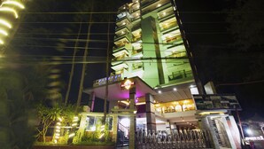 Un hôtel à plusieurs étages, doté d’une entrée imposante, d’une enseigne et d’une façade bien éclairée.
