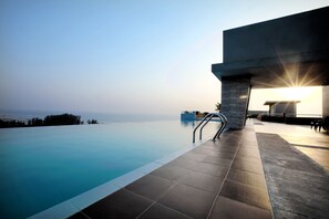 Ein moderner Infinity-Pool mit klarem, blauem Wasser, einer Betonstruktur und Blick aufs Meer.
