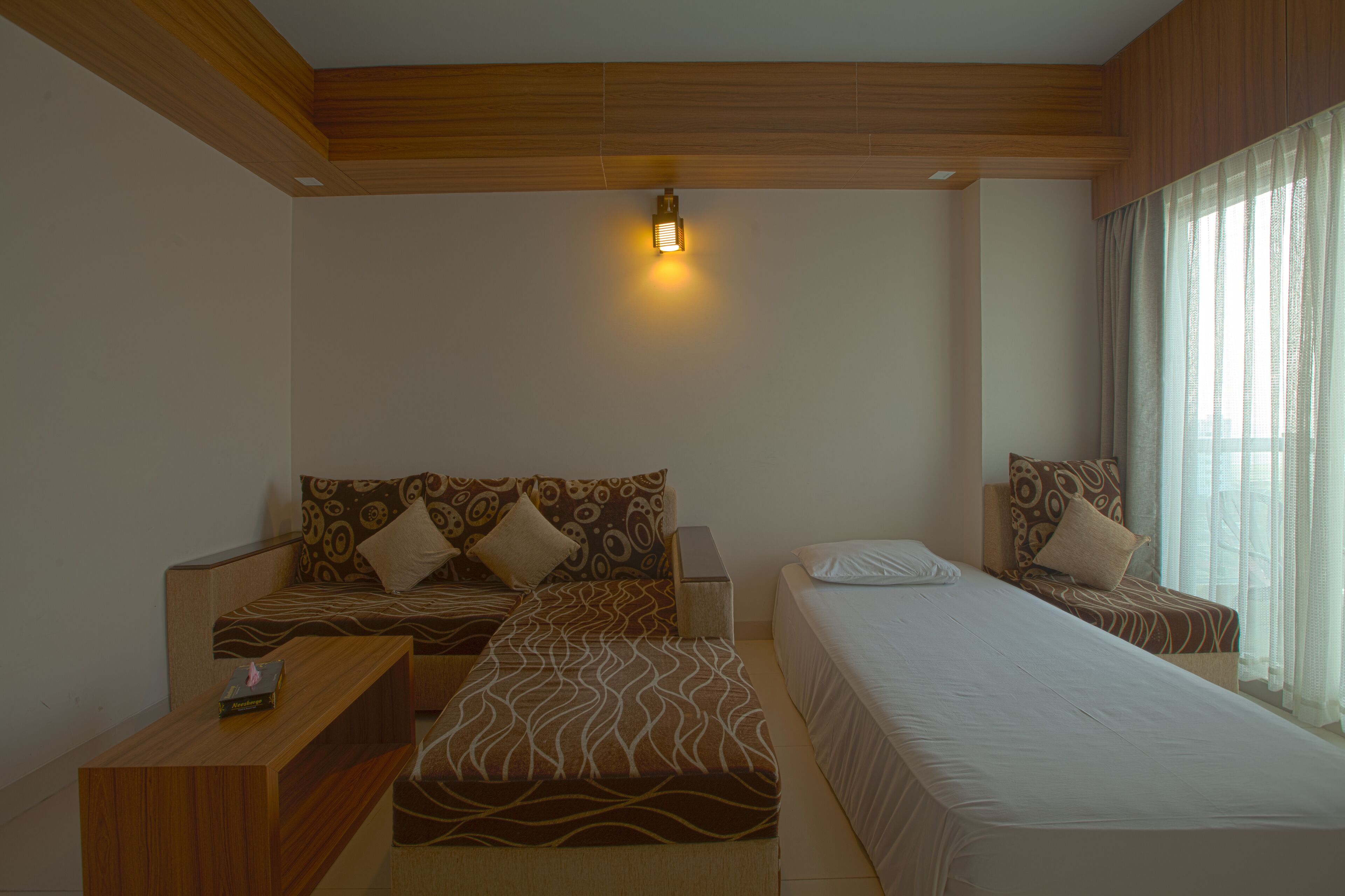 A hotel room with two beds, a wooden ceiling, a nightstand, and a bedside table.