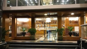 Un vestíbulo de hotel con una escalera de mármol, plantas en macetas y una recepción.