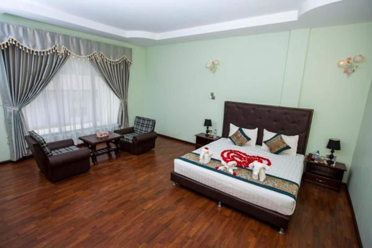 A bedroom with a large bed, a sofa, a small table, and a chair.