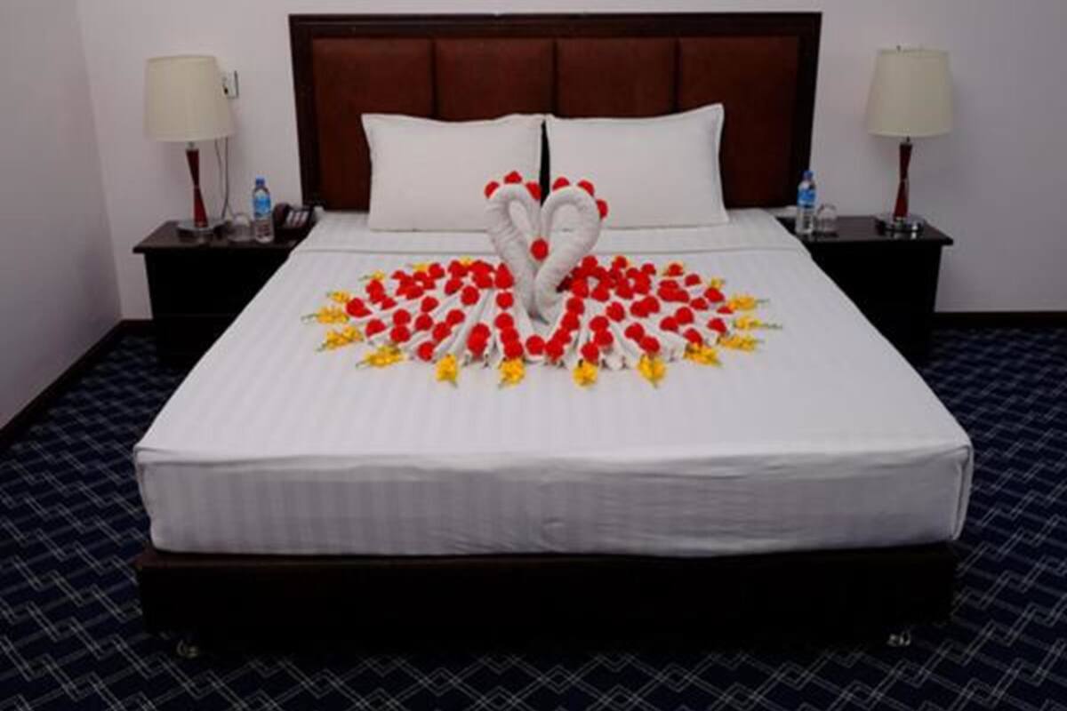 A neatly made bed with a heart-shaped floral arrangement in the center.