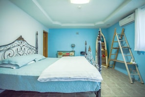 A bedroom with a bed, a dresser, a ladder, and an air conditioning unit. - Joy House (Saipan)