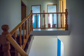 A wooden staircase with a handrail leading to a landing. - Joy House (Saipan)