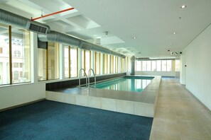 A swimming pool with clear glass walls, a blue carpeted floor, and a ceiling with recessed lighting. - Cartwrights Corner 1901 (Cape Town)