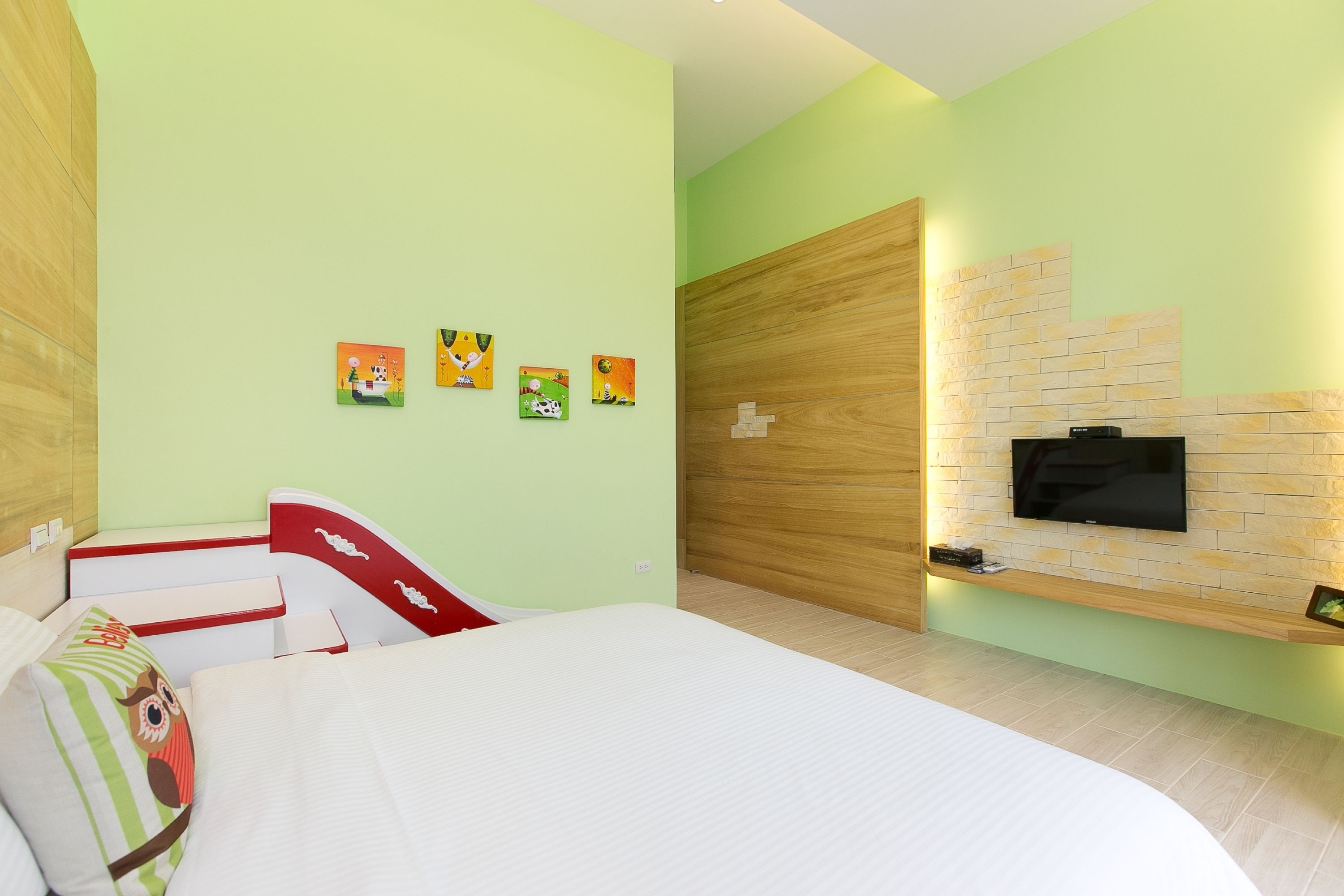 Ein Schlafzimmer mit einem Bett, einem an einer Ziegelwand befestigten Fernseher und vier Bildern an der Wand.