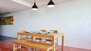 A dining area with a wooden table set for four, two pendant lights above, and a bench in front. - Rocco Condominium Hua Hin Room 811 8th F (Hua Hin)